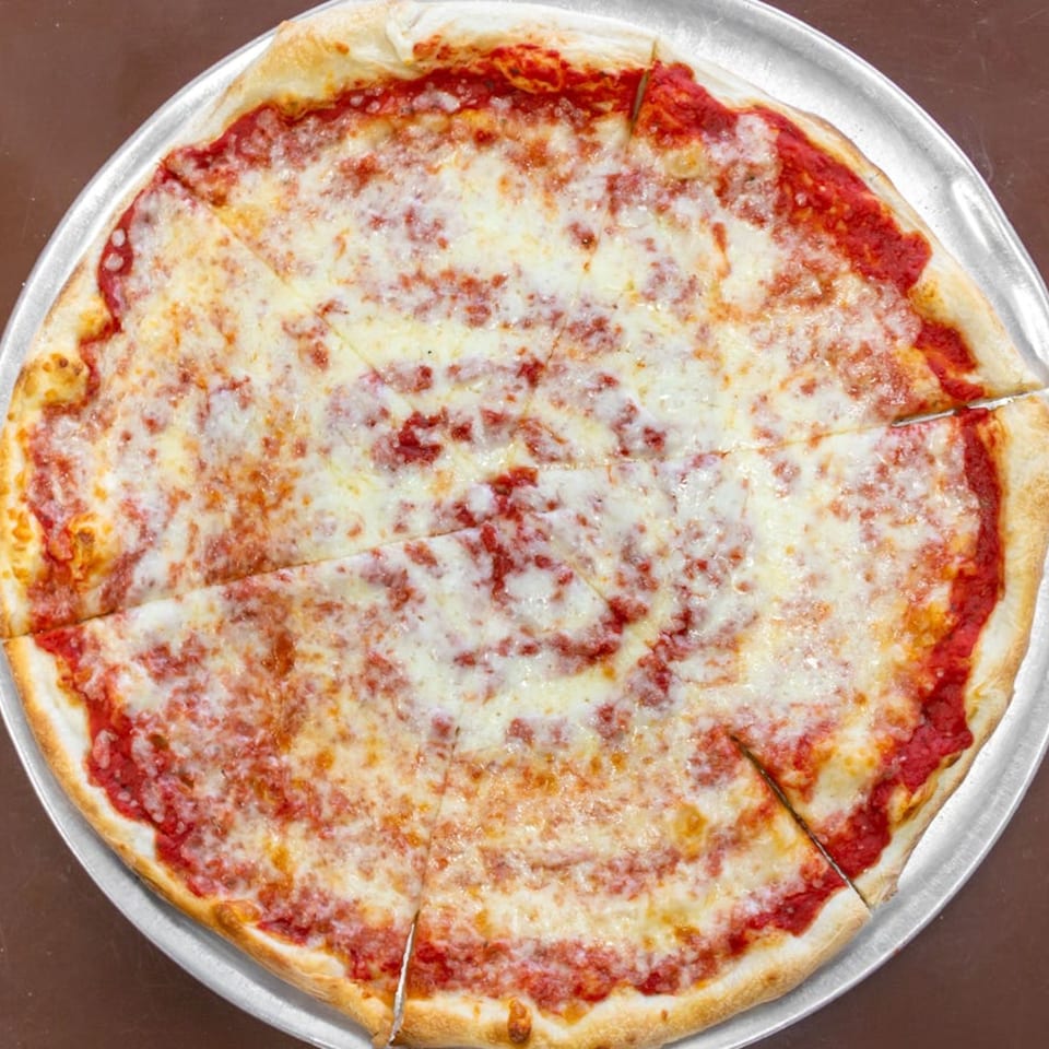A whole, sliced Carini's cheese pizza with red sauce and melted white cheese on a metal pan.