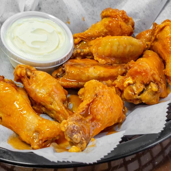 A basket of Carini's buffalo wings with a side of ranch dressing.