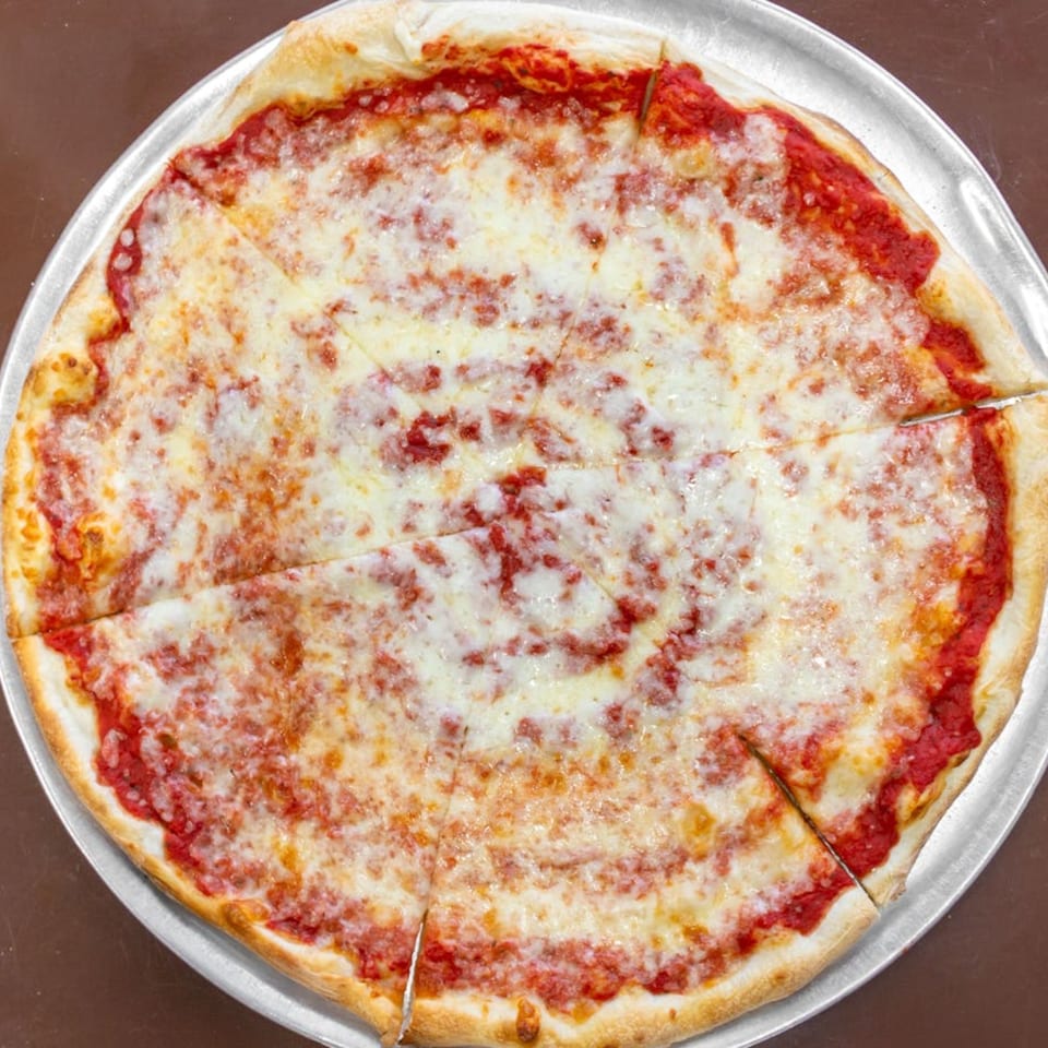 A classic Carini's cheese pizza, cut into slices, on a metal pizza pan.