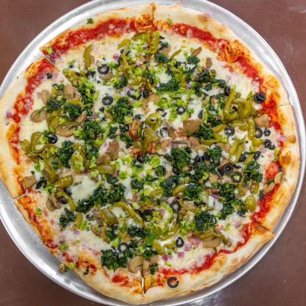 A whole Carini's Pizza with white sauce, spinach, broccoli, mushrooms, black olives, and peppers.